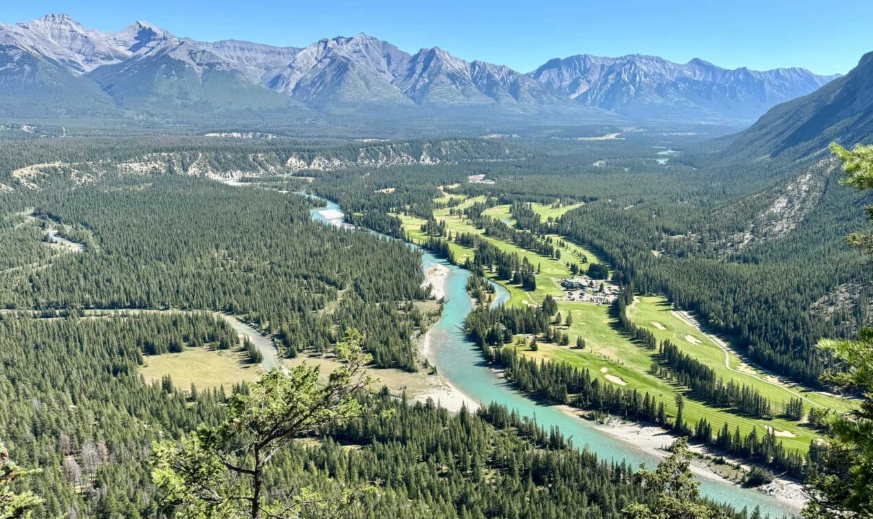 One of the stunning views from the top of Tunnel Mountain showcases the Bow River, Banff Springs Golf Course, and the majestic surrounding mountains.